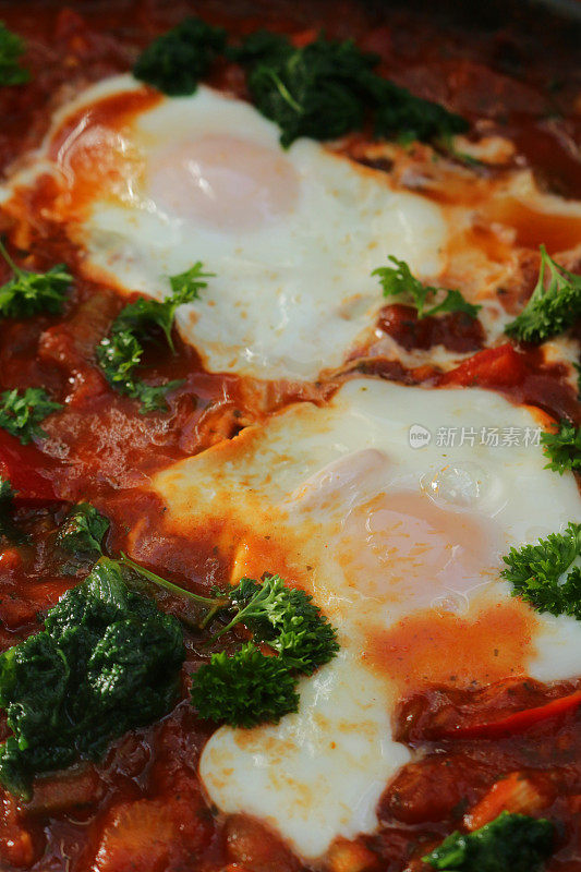 全框地中海健康早餐shakshouka / shakshuka / chakchouka在平底锅里，鸡蛋煮在西红柿、辣椒、洋葱、橄榄油和大蒜酱里，上面放上菠菜和欧芹
